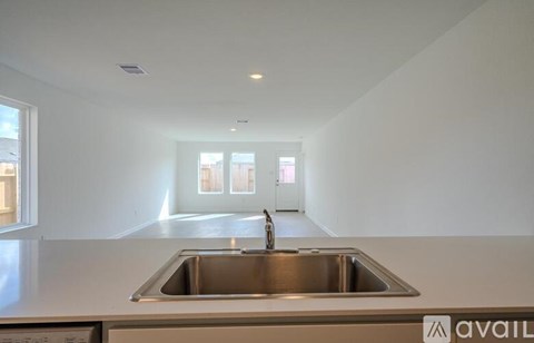 A modern kitchen with a stainless steel sink and white countertops.