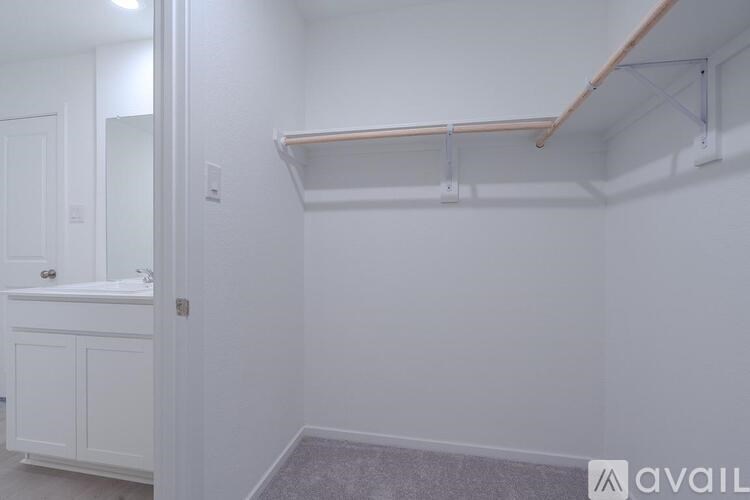 A white bathroom with a sink, mirror, and a shelf.