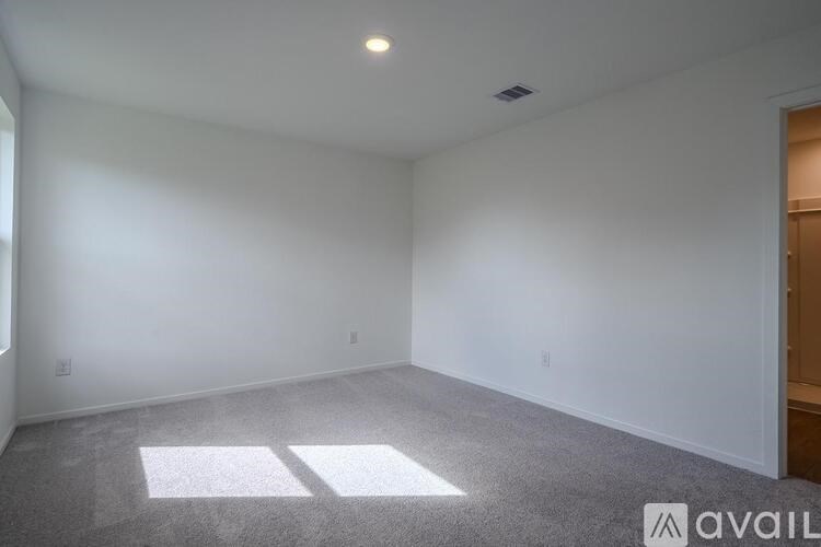 A spacious room with a carpeted floor and a window letting in natural light.