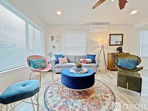 A living room with a blue ottoman and a rug with a pattern.