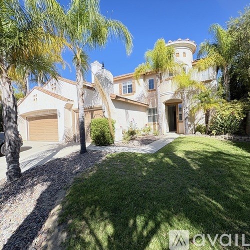 A house with a driveway and palm trees in front.