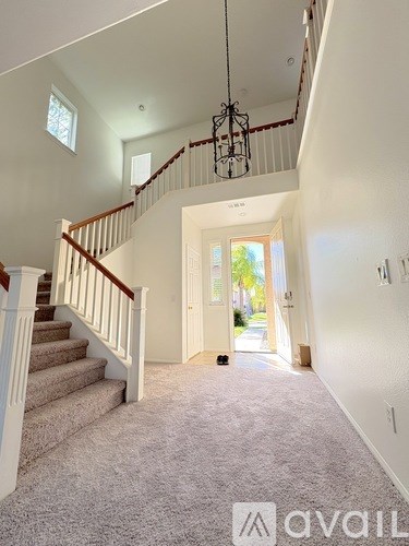 A carpeted hallway with a staircase leading to the second floor.