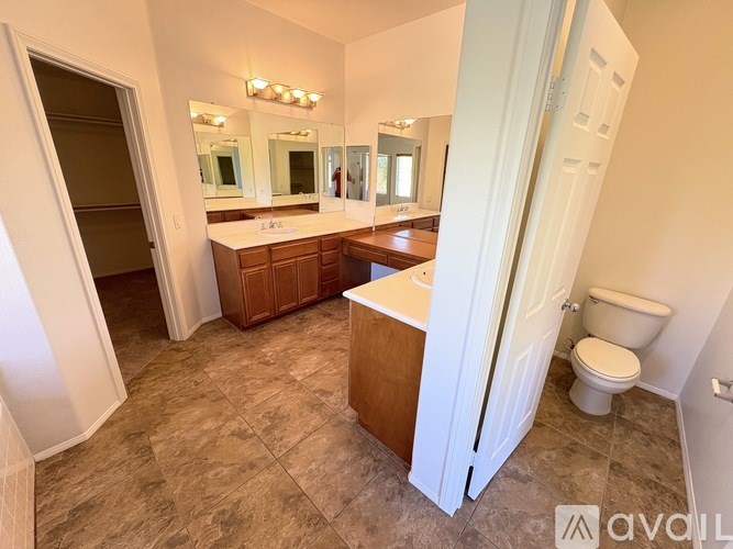 A bathroom with a toilet, sink, and mirrors.