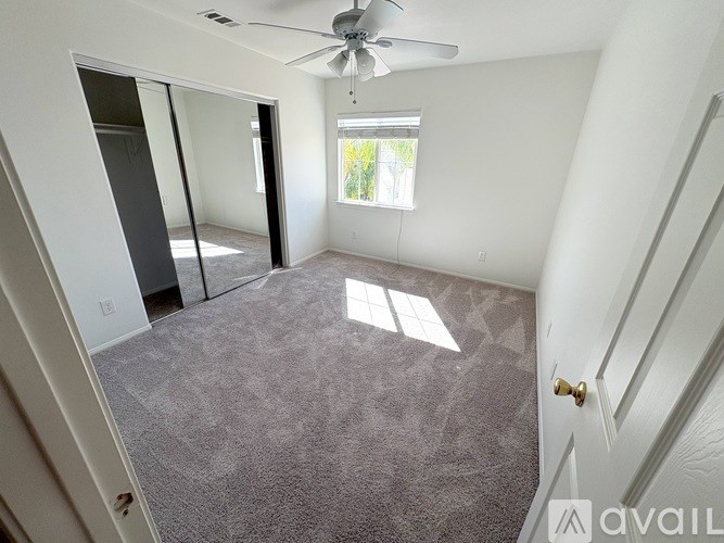 A room with a carpeted floor and a ceiling fan.