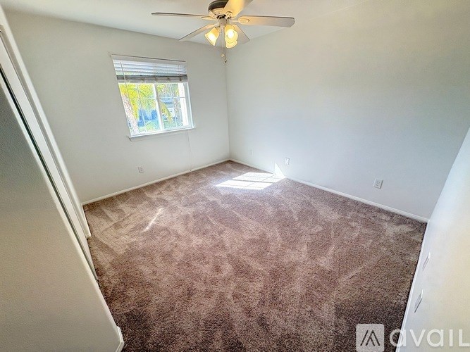 A room with a ceiling fan and carpeted floor.
