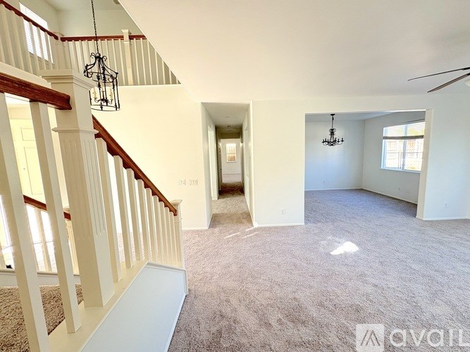 A spacious room with a carpeted floor and a staircase with wooden railings.