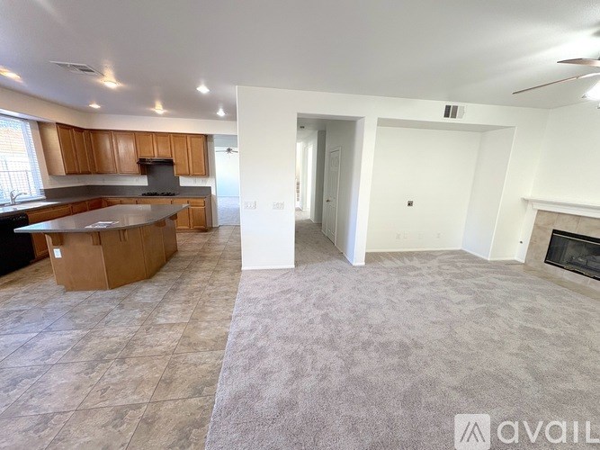 A living room with a fireplace and a kitchen area with wooden cabinets.