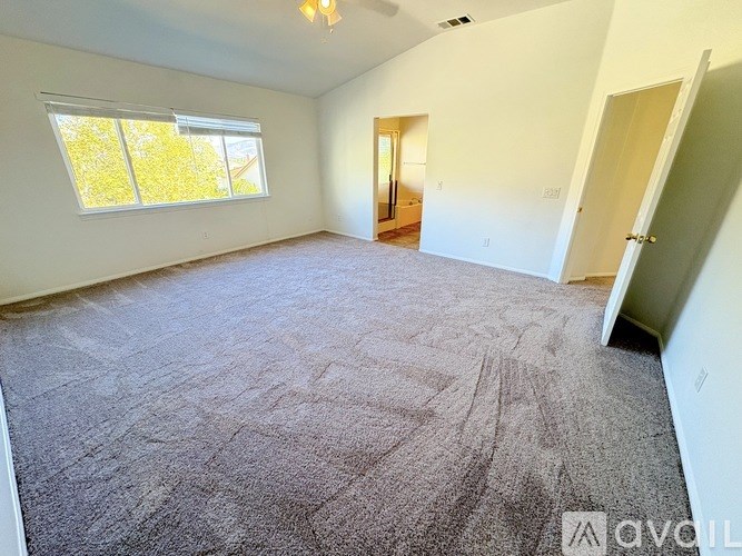 A spacious room with a carpeted floor and a window with yellow blinds.
