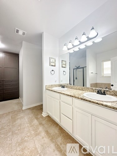 A bathroom with a sink, mirror, and lighting fixture.