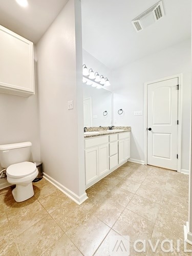 A bathroom with a toilet, sink, and mirror.