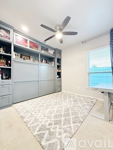 A room with a ceiling fan and a rug on the floor.