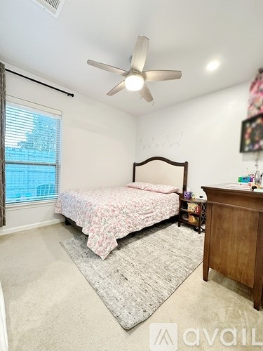 A bedroom with a bed, a ceiling fan, and a window with blinds.