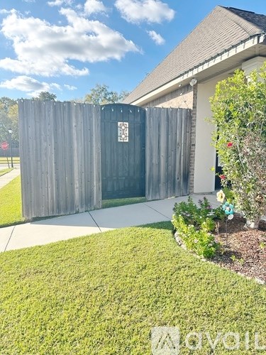 A wooden fence with a gate and a house in the background.