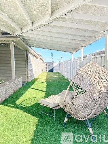 A patio with a white chair and a white umbrella.