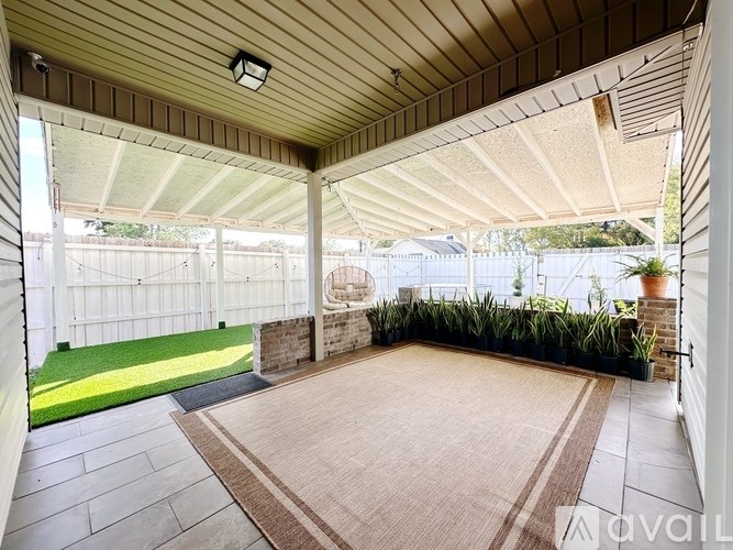 A patio with a rug and a white fence.