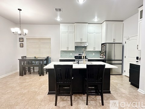 A kitchen with black chairs and a white island.