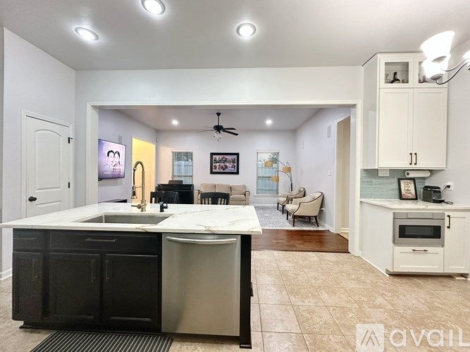 A kitchen with a black countertop and a stainless steel dishwasher.