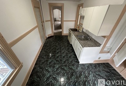 A kitchen with a marble floor and white cabinets.