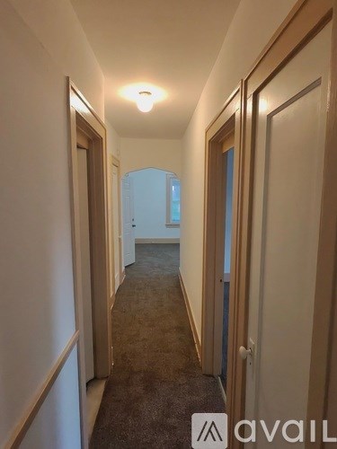 A hallway with a carpeted floor and a light on the ceiling.