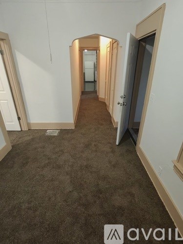 A hallway with a carpeted floor and white walls.