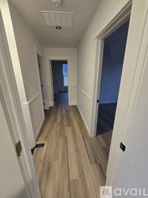 A long hallway with wood floors and white walls.