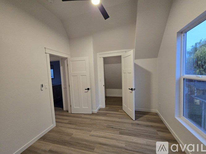 A room with a ceiling fan and two doors.