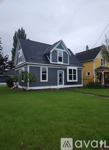 A house with a grey front and a green lawn.
