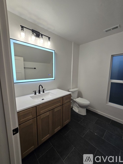 A bathroom with a sink, toilet, and mirror.
