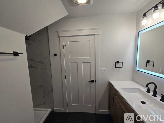 A bathroom with a marble wall and a white door.