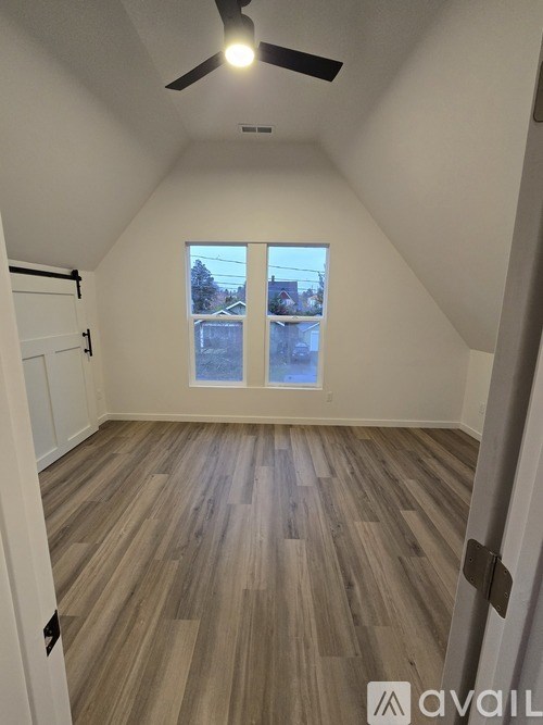 A room with a ceiling fan and wooden flooring.