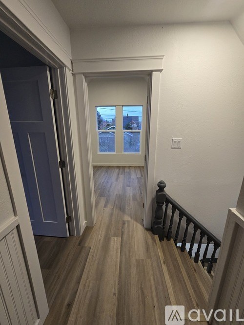 A hallway with a wooden floor and a balcony with a railing.