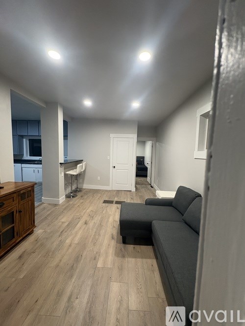 A living room with a grey couch and wooden flooring.