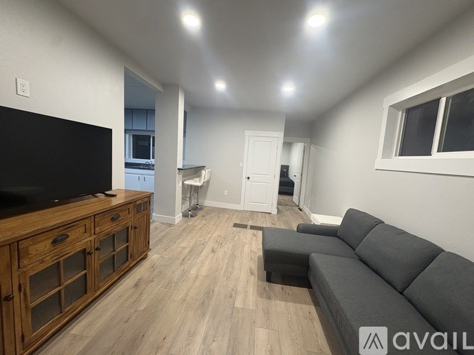 A living room with a grey couch and a wooden cabinet with a flat screen TV on top.