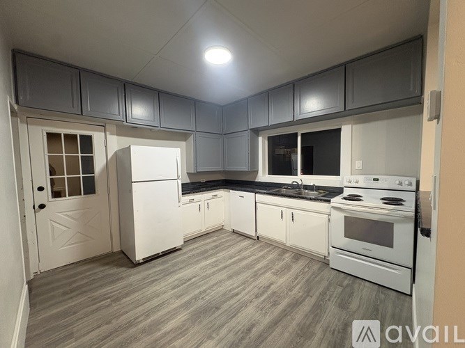 A kitchen with white appliances and wooden flooring.
