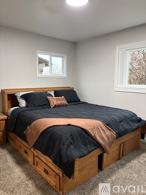 A bed with a black comforter and an orange throw is in the image.