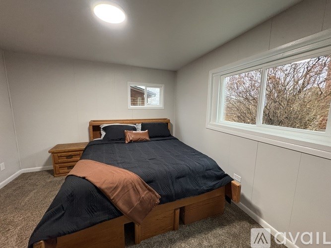 A bedroom with a bed, nightstand, and window.