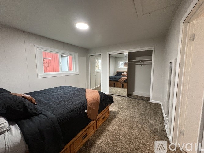 A bedroom with a bed, a mirror, and a window.