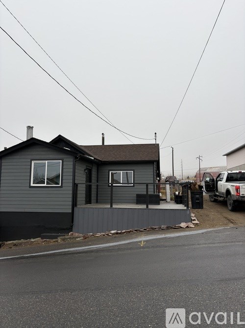 A grey house with a black roof and a grey fence.