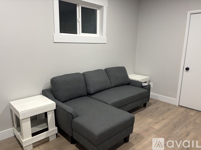 A grey sectional sofa with a white side table in front of a white door.