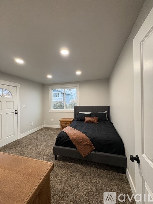A bedroom with a bed, nightstand, and window.