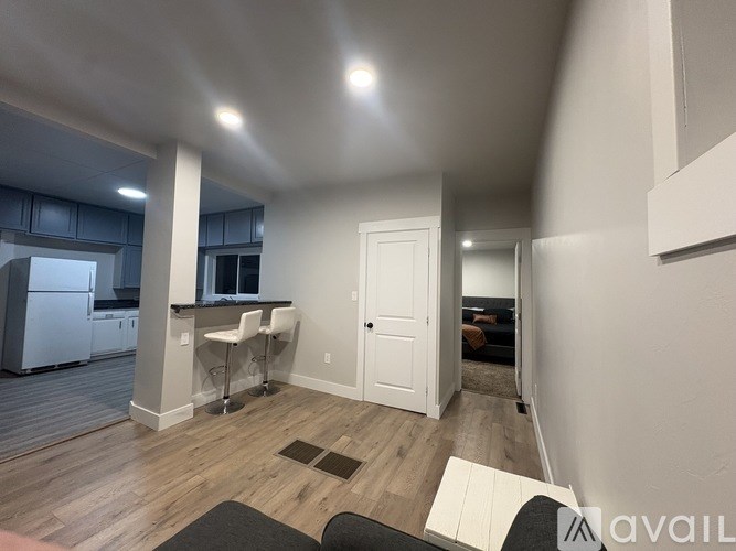 A kitchen area with a refrigerator, a bar area with stools, and a living area with a couch.