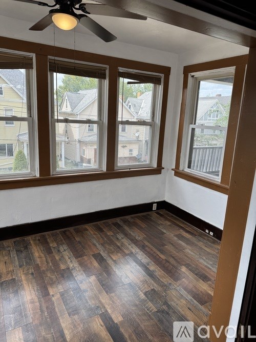 A room with wooden flooring and three windows.