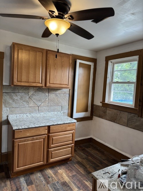 A kitchen with wooden cabinets and a ceiling fan.