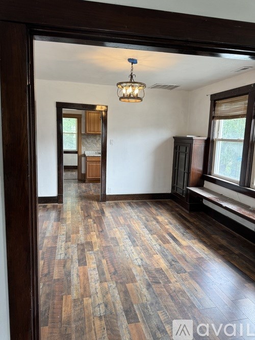 A room with wooden floors and a chandelier hanging from the ceiling.