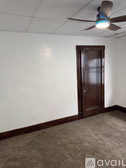 A room with a ceiling fan and a brown door.
