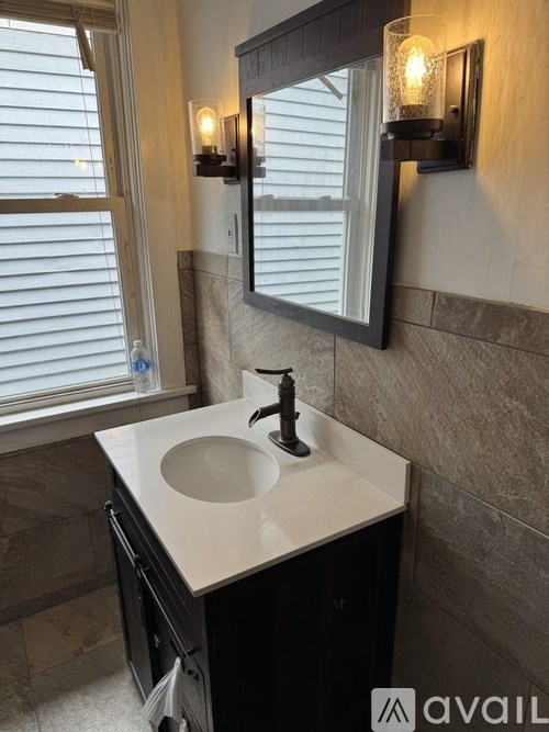A bathroom with a sink, mirror, and light fixture.