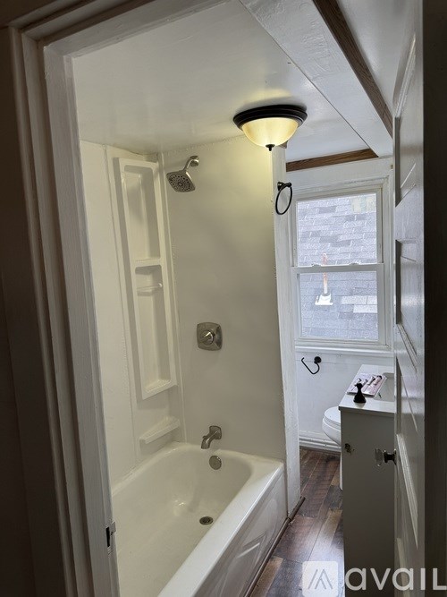 A bathroom with a white tub and a window.