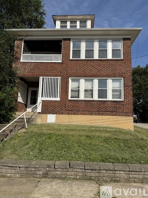 A two-story brick house with a balcony on the second floor.