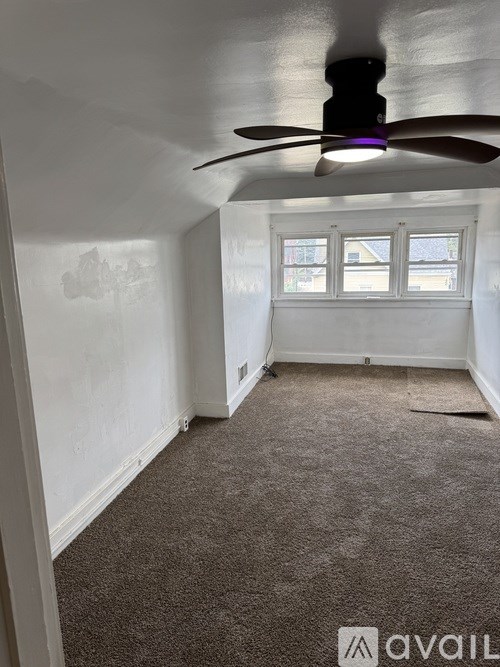 A room with a ceiling fan and carpeted floor.