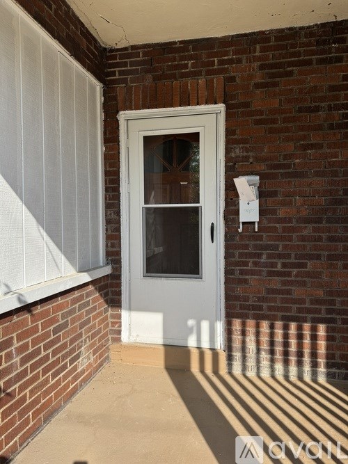 A white door with a glass window is set in a brick wall.